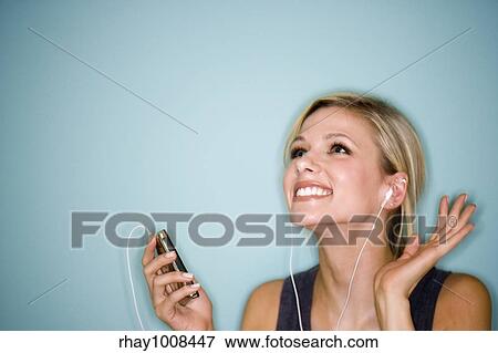Stock Photo - Smiling pretty woman with earbuds listening to MP3 player. Fotosearch