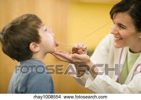 Smiling woman doctor examining child patient with tongue depressor View Large Photo Image Picture - Smiling woman doctor examining child patient with tongue depressor. Fotosearch