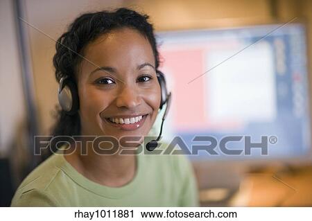 Stock Image - Smiling young African American woman with headset and microphone. Fotosearch