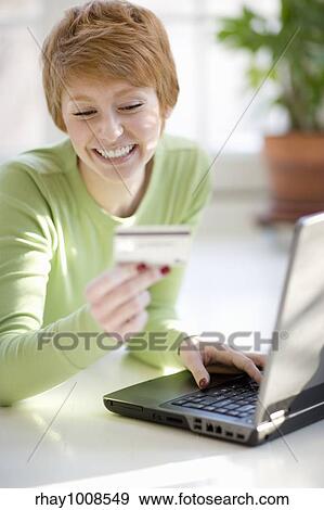 Smiling young woman shopping online with credit card and laptop computer View Large Photo Image Stock Photo - Smiling young woman shopping online with credit card and laptop computer. Fotosearch