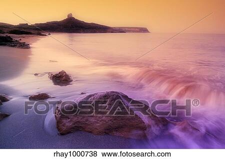 Stock Photo - "sunrise on a rocky shore in Sardinia, Italy". Fotosearch