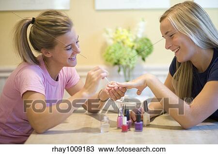 Stock Image - Teen friends doing manicures for each other. Fotosearch