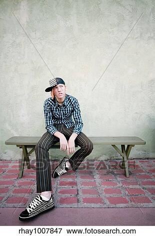 Teenage boy sitting on a green bench in front of a stucco wall View Large Photo Image Stock Photo - Teenage boy sitting on a green bench in front of a stucco wall. Fotosearch
