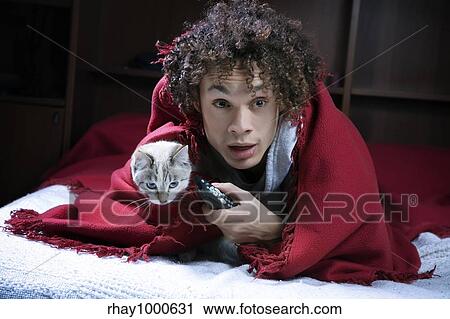 Stock Image - terrified guy watching a horror movie on tv. Fotosearch
