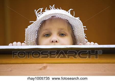 The little girl in a summer hat looks out of a window of a wooden country houseThe little girl in a summer hat looks out of a window of a wooden country house View Large Photo Image Stock Photography - The little girl in a summer hat looks out of a window of a wooden country houseThe little girl in a summer hat looks out of a window of a wooden country house. Fotosearch