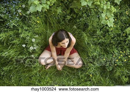 Picture - The top view on the girl-teenager sitting on a green grassThe top view on the girl-teenager sitting on a green grass. Fotosearch
