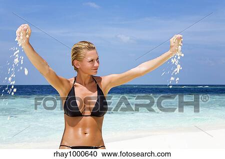 Stock Image - tropical beach: perfect girl playing with sand on a tropical beach. Fotosearch