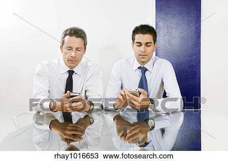 Two businessmen checking blackberries in meeting room. View Large Photo Image Stock Image - Two businessmen checking blackberries in meeting room.. Fotosearch