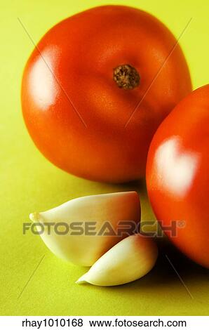 two tomatoes with two garlic cloves on bright green surface View Large Photo Image Stock Photo - two tomatoes with two garlic cloves on bright green surface. Fotosearch