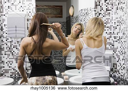 Stock Photograph - two women in toilet applying make up. Fotosearch