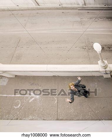 Wide shot from above of woman on a sidewalk with her hands in the air View Large Photo Image Stock Image - Wide shot from above of woman on a sidewalk with her hands in the air. Fotosearch