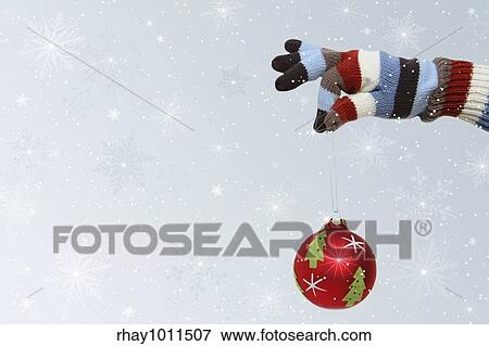 Winter mitten holding a Christmas ball View Large Photo Image Stock Photo - Winter mitten holding a Christmas ball. Fotosearch