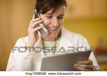 Woman doctor talking on cell phone and looking at a medical chart View Large Photo Image Stock Photograph - Woman doctor talking on cell phone and looking at a medical chart. Fotosearch