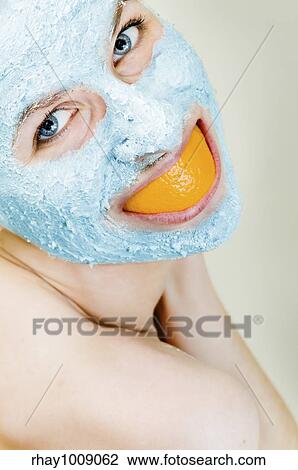 Stock Image - woman goofing aroung with orange skin smile while waiting for her clay mask to affect. Fotosearch