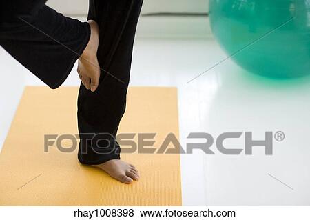 Stock Photo - Young African American woman in yoga Tree pose only legs showing. Fotosearch