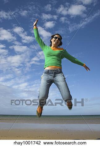 Young beautiful woman making a big jump on the beach View Large Photo Image Stock Image - Young beautiful woman making a big jump on the beach. Fotosearch