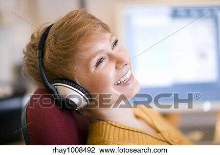 Young laughing woman relaxing in chair listening to headphones View Large Photo Image Stock Image - Young laughing woman relaxing in chair listening to headphones. Fotosearch