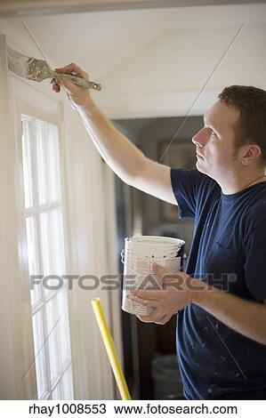Young man painting door trim inside a house View Large Photo Image Stock Image - Young man painting door trim inside a house. Fotosearch
