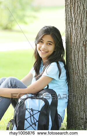 "Young teen girl sitting against tree with backpack. Part Asian, Scandinavian background. " View Large Photo Image Stock Photograph - "Young teen girl sitting against tree with backpack. Part Asian, Scandinavian background. ". Fotosearch