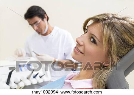 young woman doing dental checkup. Dentist in the background View Large Photo Image Picture - young woman doing dental checkup. Dentist in the background. Fotosearch