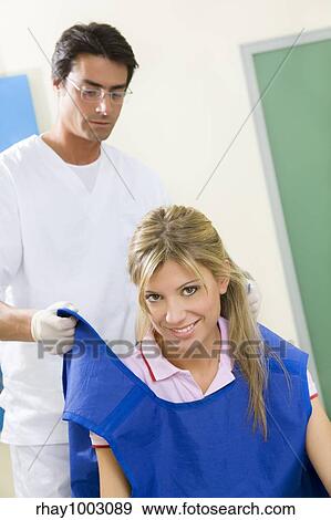 young woman doing dental checkup with x-ray. Dentist is covering her with a protective lead coat View Large Photo Image Stock Photo - young woman doing dental checkup with x-ray. Dentist is covering her with a protective lead coat. Fotosearch