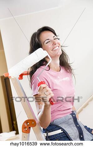 Young woman holding paint roller and smiling View Large Photo Image Stock Photo - Young woman holding paint roller and smiling. Fotosearch