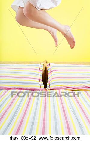 young woman jumping on bed with striped sheet View Large Photo Image Stock Image - young woman jumping on bed with striped sheet. Fotosearch