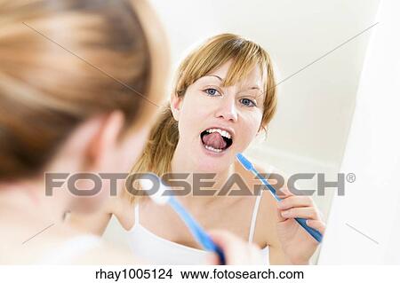 Young woman looking into a mirror brushing her teeth View Large Photo Image Picture - Young woman looking into a mirror brushing her teeth. Fotosearch