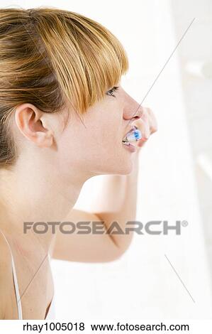 Young woman looking into a mirror brushing her teeth View Large Photo Image Stock Photo - Young woman looking into a mirror brushing her teeth. Fotosearch