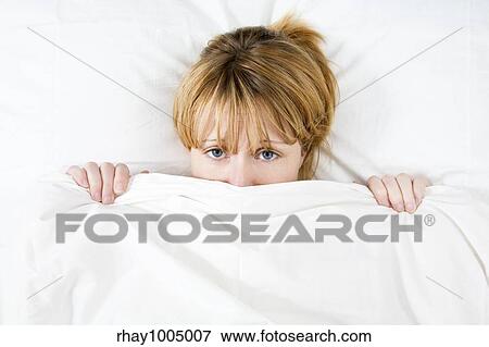 Stock Photo - Young woman lying in bed doesn't want to wake up . Fotosearch
