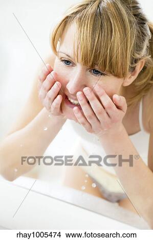 young woman washing her face in a basin and looking herself in the mirror View Large Photo Image Picture - young woman washing her face in a basin and looking herself in the mirror. Fotosearch