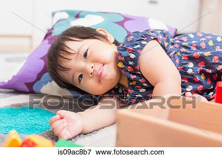 Stock Photo - Baby girl playing on floor. Fotosearch