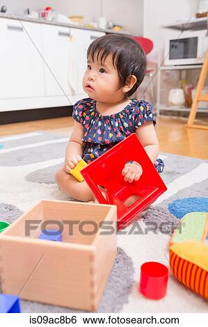 Stock Photograph - Baby girl playing on floor. Fotosearch