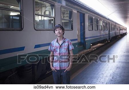 Picture - Boy by train with hands in pockets. Fotosearch