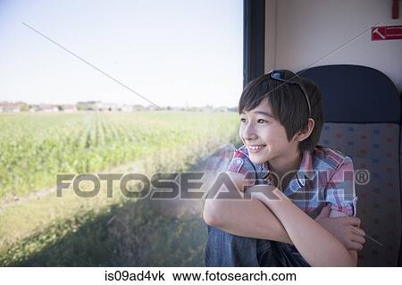 Stock Image - Boy looking out of train window. Fotosearch