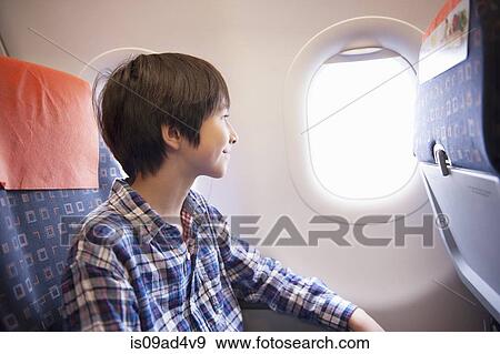 Boy looking out of window on aeroplane View Large Photo Image Stock Photo - Boy looking out of window on aeroplane. Fotosearch