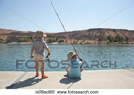 Stock Image - Boys fishing by lake. Fotosearch