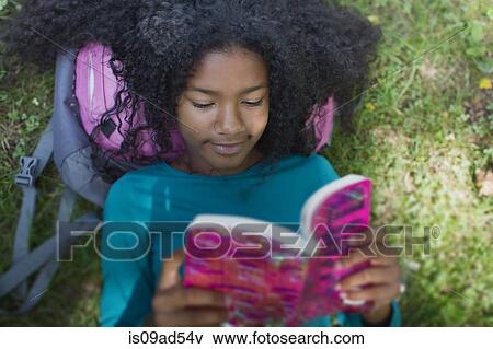 Stock Photo - Close up of girl reading in park. Fotosearch