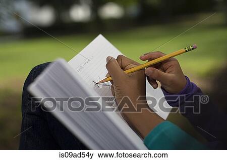 Close up of sisters in park writing in notebook View Large Photo Image Stock Photo - Close up of sisters in park writing in notebook. Fotosearch