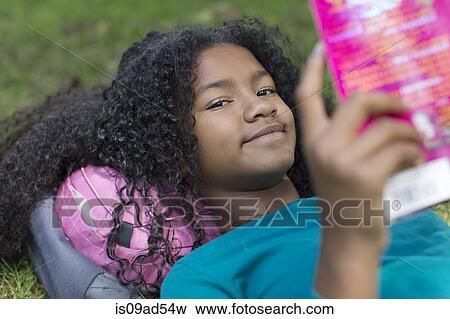 Close up portrait of young girl reading in park View Large Photo Image Stock Photo - Close up portrait of young girl reading in park. Fotosearch