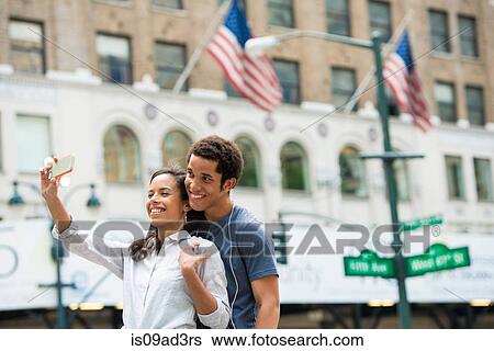 Stock Photograph - Couple taking photograph with mobile phone. Fotosearch