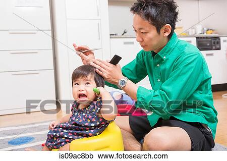 Stock Image - Father cutting baby's hair on floor. Fotosearch