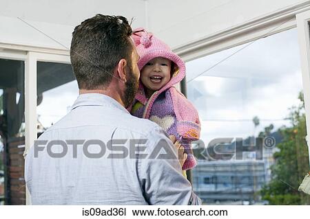 Father dressing daughter in hooded knitted top View Large Photo Image Stock Image - Father dressing daughter in hooded knitted top. Fotosearch