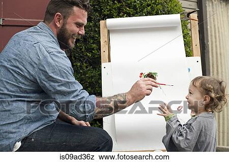 Stock Photo - Father fooling around painting on daughter's face. Fotosearch