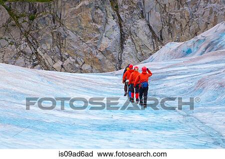 Stock Image - Four people walking on Mendenhall Glacier, Alaska, USA. Fotosearch