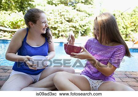 Stock Image - Friends eating by pool. Fotosearch