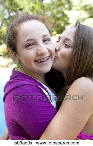 Stock Image - Friends hugging and kissing on cheek. Fotosearch
