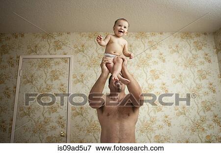 Stock Photo - Grandfather holding baby granddaughter, low angle. Fotosearch