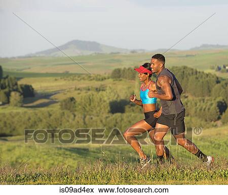 Stock Photo - Man and woman running in landscape, Othello, Washington, USA. Fotosearch