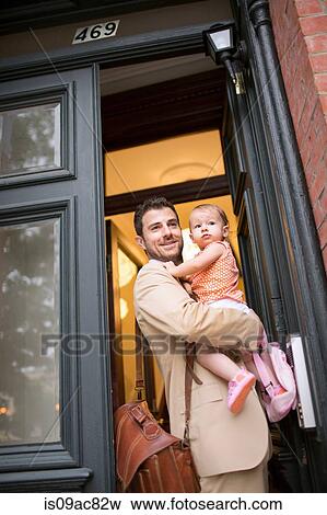 Man holding baby standing at front door View Large Photo Image Stock Photo - Man holding baby standing at front door. Fotosearch